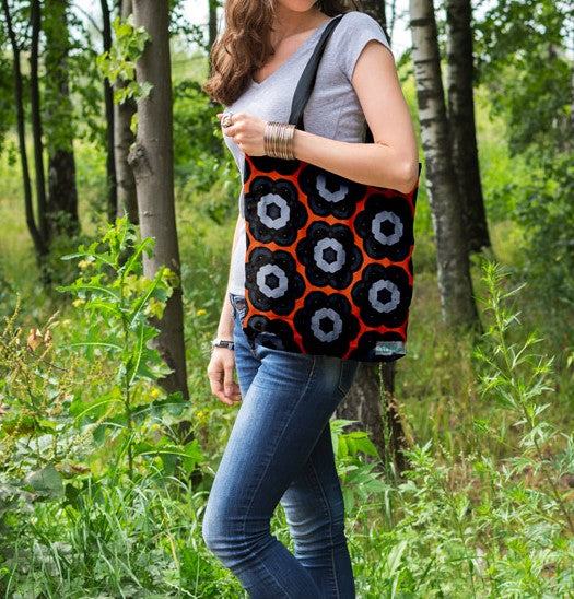 Woman walking amongst trees carrying the Garden Tiger tote bag on her shoulder. Designed by Anne Harrington Rees. Designed, printed and made in Ireland.