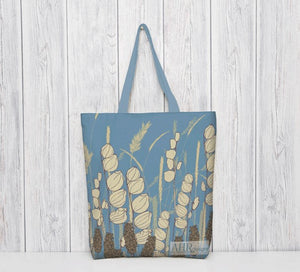 Colourful gift – Blue and Cream Meadow Sky tote bag with a blue handle hanging in front of bleached wooden panel. Designed by Anne Harrington Rees. Designed, printed and made in Ireland.
