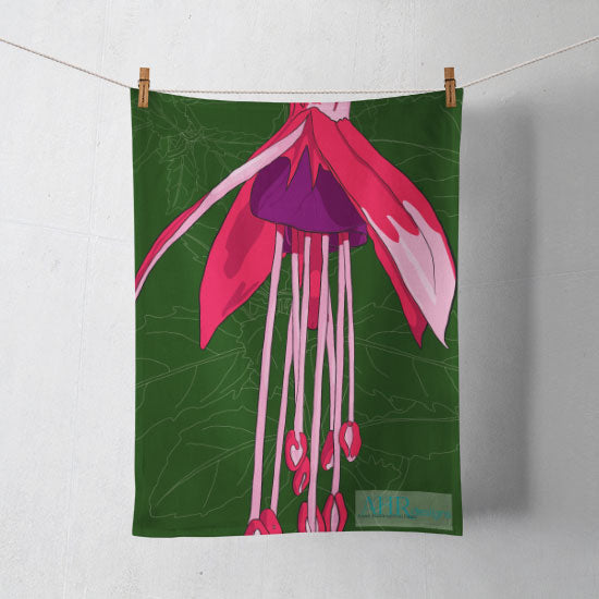 Colourful gift – Pink, Purple and Green Fuchsia flower design tea towel hanging from clothesline, shadows showing on off-white background. Designed by Anne Harrington Rees. Designed, printed and made in Ireland.