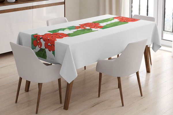 Holly table runner designed by Anne Harrington Rees, shown laid on a table with a white tablecloth underneath.  The design features red berries and spiny green leaves on a white background.