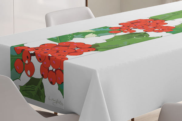 Close up of the Holly table runner designed by Anne Harrington Rees, shown laid on a table with a white tablecloth underneath.  The design features red berries and spiny green leaves on a white background.