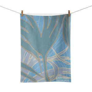 Colourful gift – Blue, Turquoise and Sand Kelp seaweed design tea towel hanging from clothesline, white background. Designed by Anne Harrington Rees. Designed, printed and made in Ireland.
